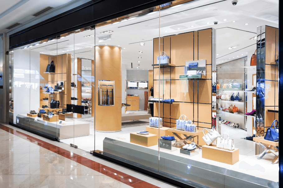 Luxury retail store with glass windows showcasing handbags and shoes on display shelves.